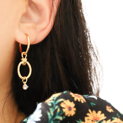 Woman wearing gold drop hoop earrings