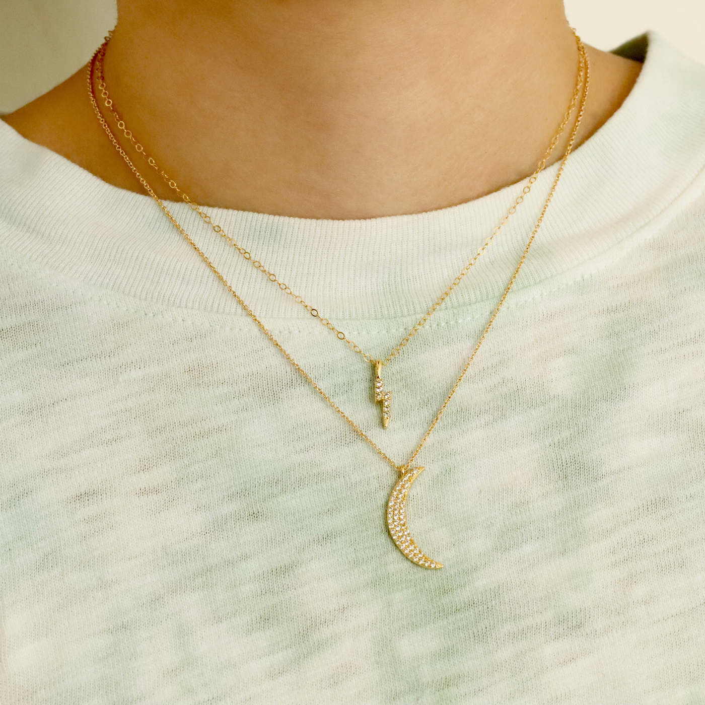 Woman wearing moon pendant necklace and thunder bolt necklace